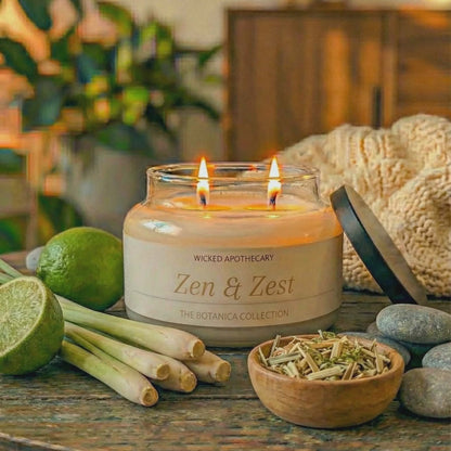Candle labeled 'Zen & Zest' on a table with limes, lemongrass, and stones.