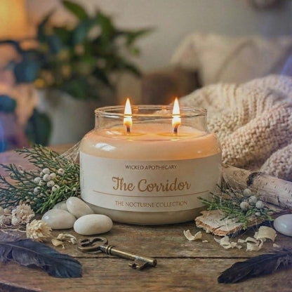 Two lit candles in a glass jar on a wooden surface with decorative elements.