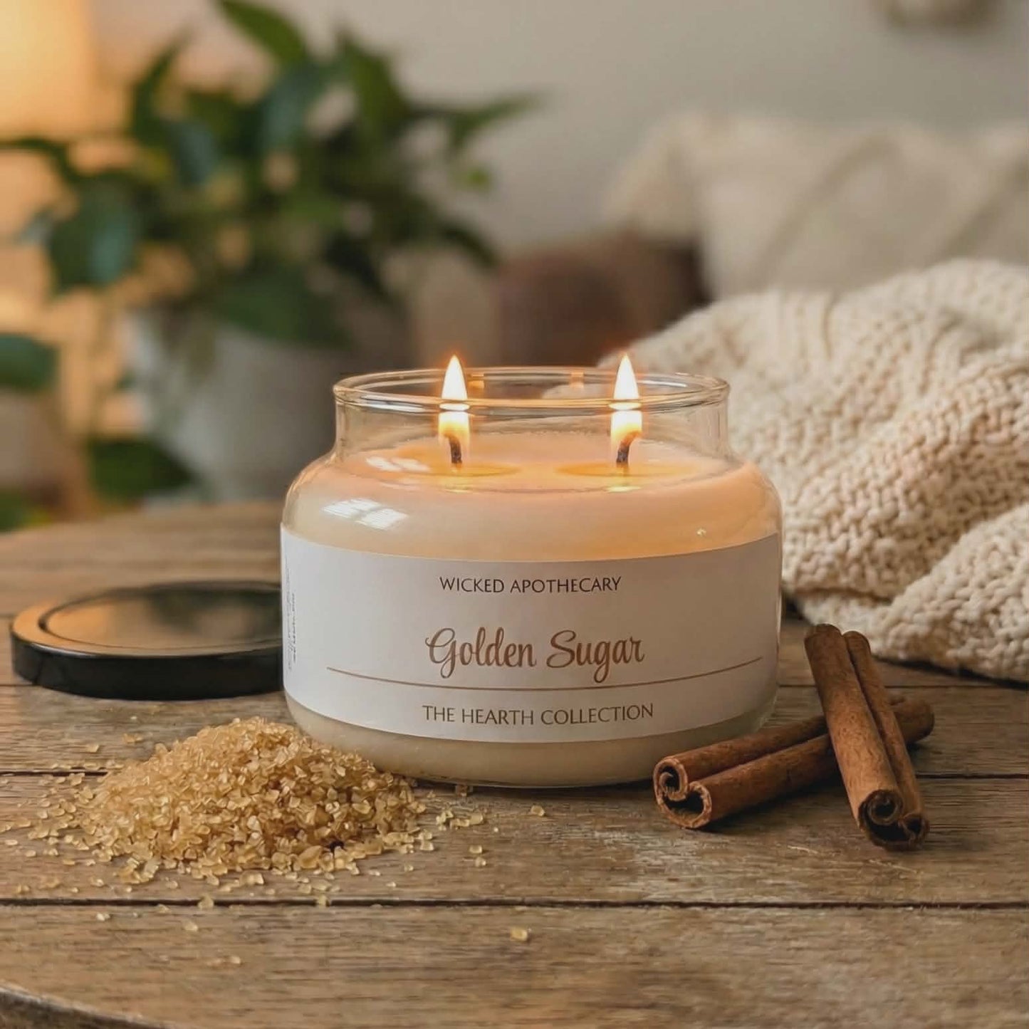 Candle labeled 'Golden Sugar' from Wicked Apothecary on a wooden table with cinnamon sticks and brown sugar.