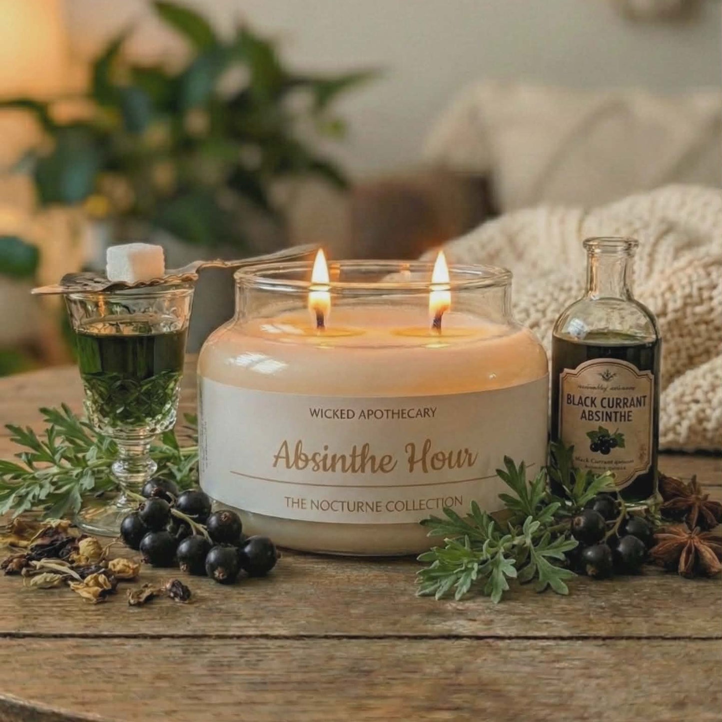 Candle labeled 'Absinthe Hour' from Wicked Apothecary on a wooden table with bottles and greenery.