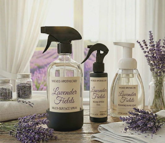 Three bottles of Wicked Apothecary Lavender Fields products on a wooden surface with lavender flowers.