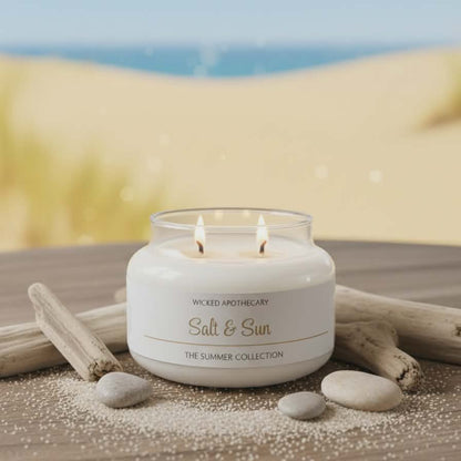 Candle labeled 'Salt & Sun' from Wicked Apothecary on a sandy background