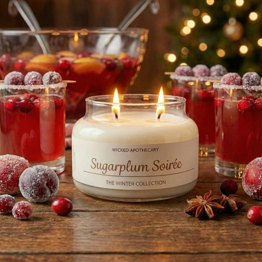 Candle labeled 'Sugarplum Soireé' with festive drinks and decorations on a wooden surface.