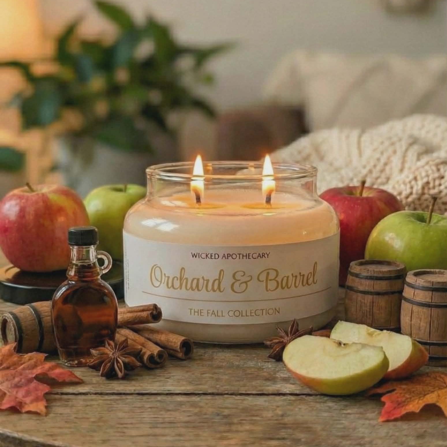 Wicked Apothecary Orchard & Barrel candle on a wooden table with apples, cinnamon, and a bottle of syrup.