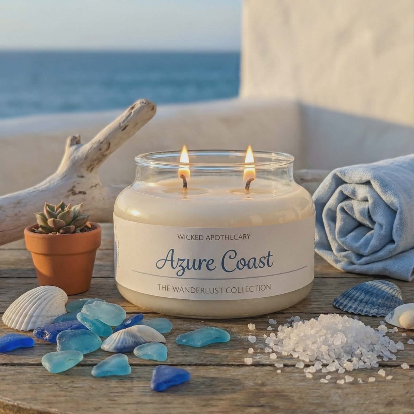 Wicked Apothecary Azure Coast candle on a wooden table with beach decor and ocean view.