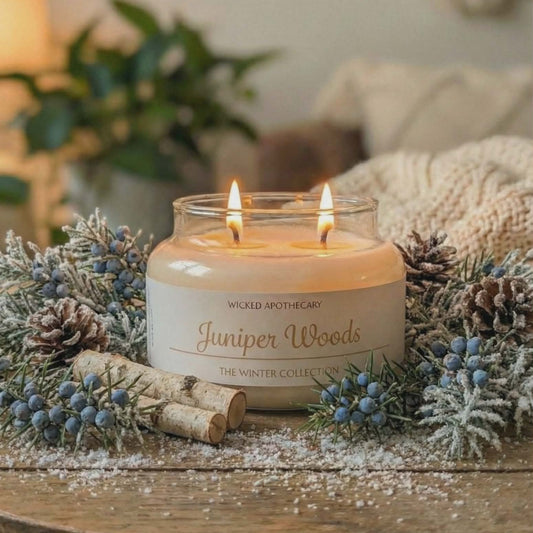Candle labeled 'Juniper Woods' on a wooden table with decorative elements