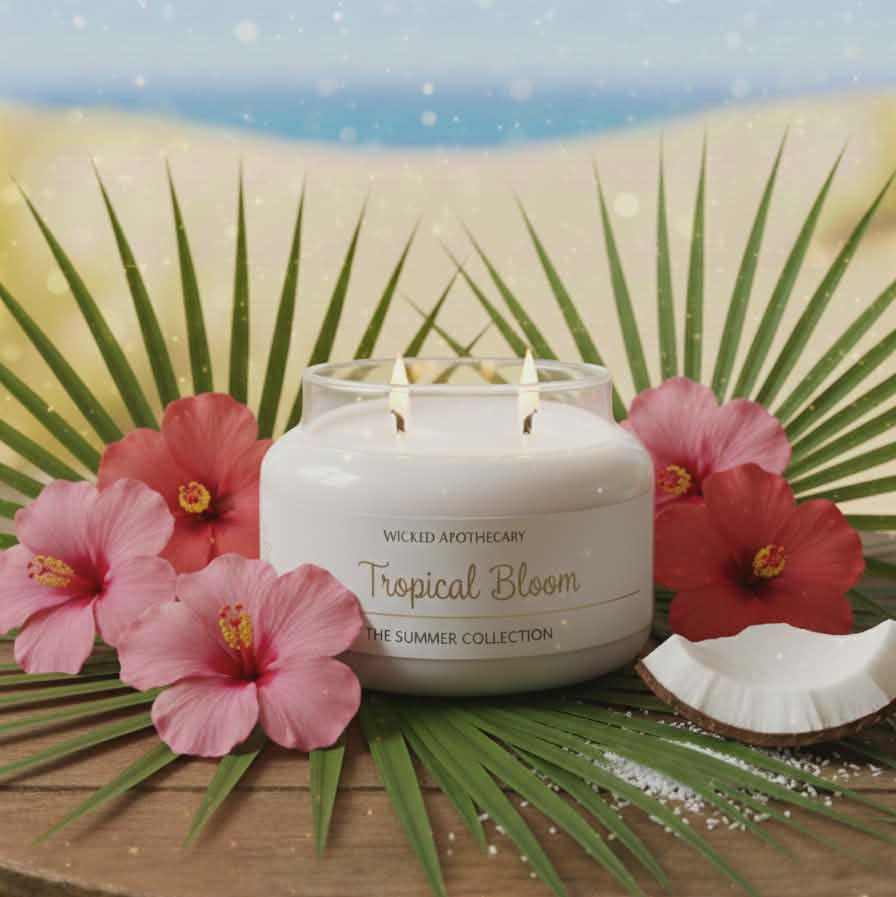 Candle labeled 'Tropical Bloom' with pink flowers and a palm leaf on a decorative surface.
