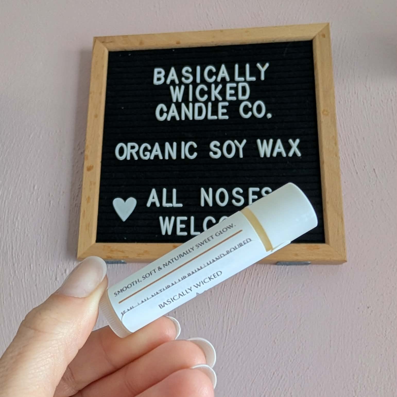Hand holding a product with a letterboard displaying 'Basically Wicked Candle Co.'
