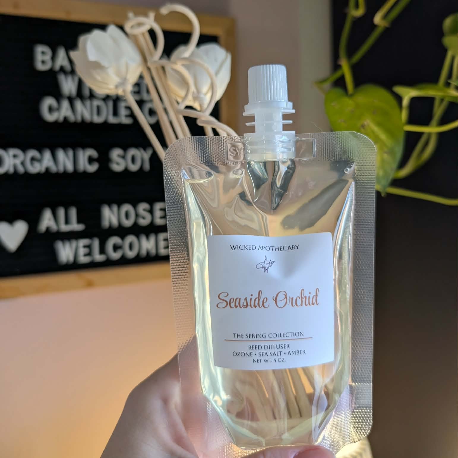 Hand holding a clear bag with a label, likely containing a product, against a blurred background.