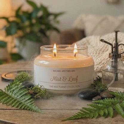 Candle labeled 'Wicked Apothecary Mist & Leaf' on a wooden table with decorative elements.