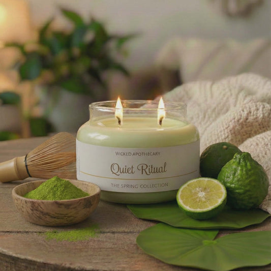 Candle labeled 'Quiet Ritual' on a wooden table with greenery and a bowl of matcha powder.