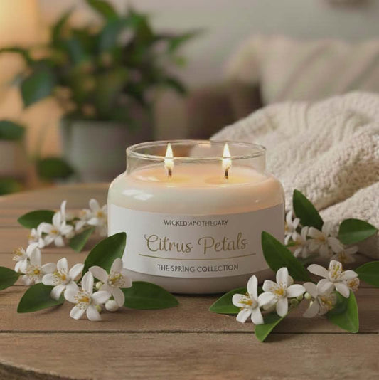 Candle labeled 'Citrus Petals' on a wooden surface with flowers and greenery.