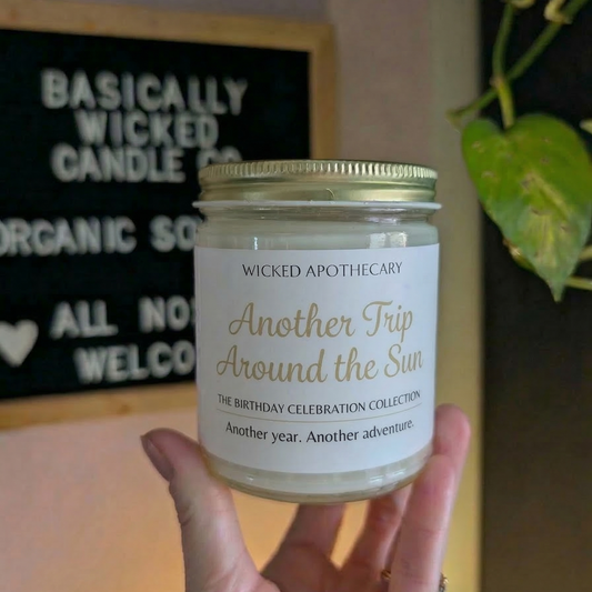 Candle labeled 'Wicked Apothecary' held by a hand with a blurred background