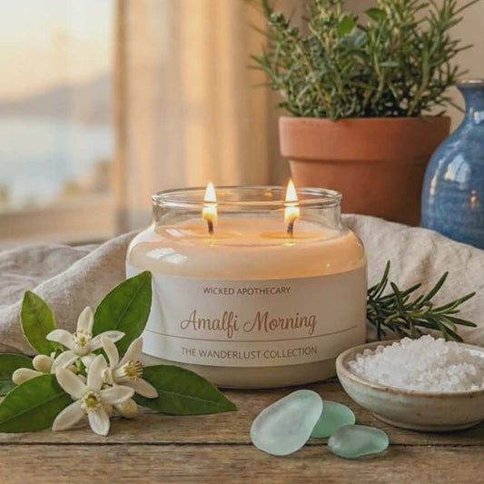 Wicked Apothecary candle with flowers, seaglass, and a plant on a wooden surface.