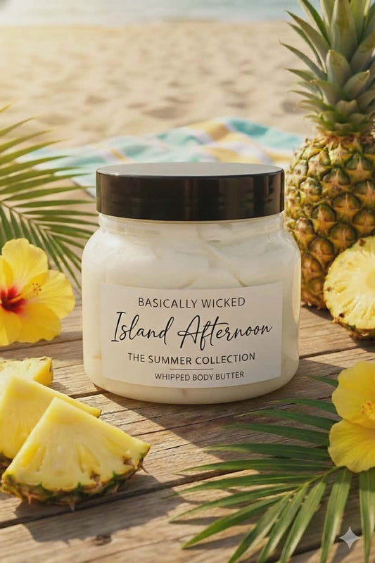 Whipped body butter jar labeled 'Basically Wicked Island Afternoon' with pineapple slices and leaves on a wooden surface.