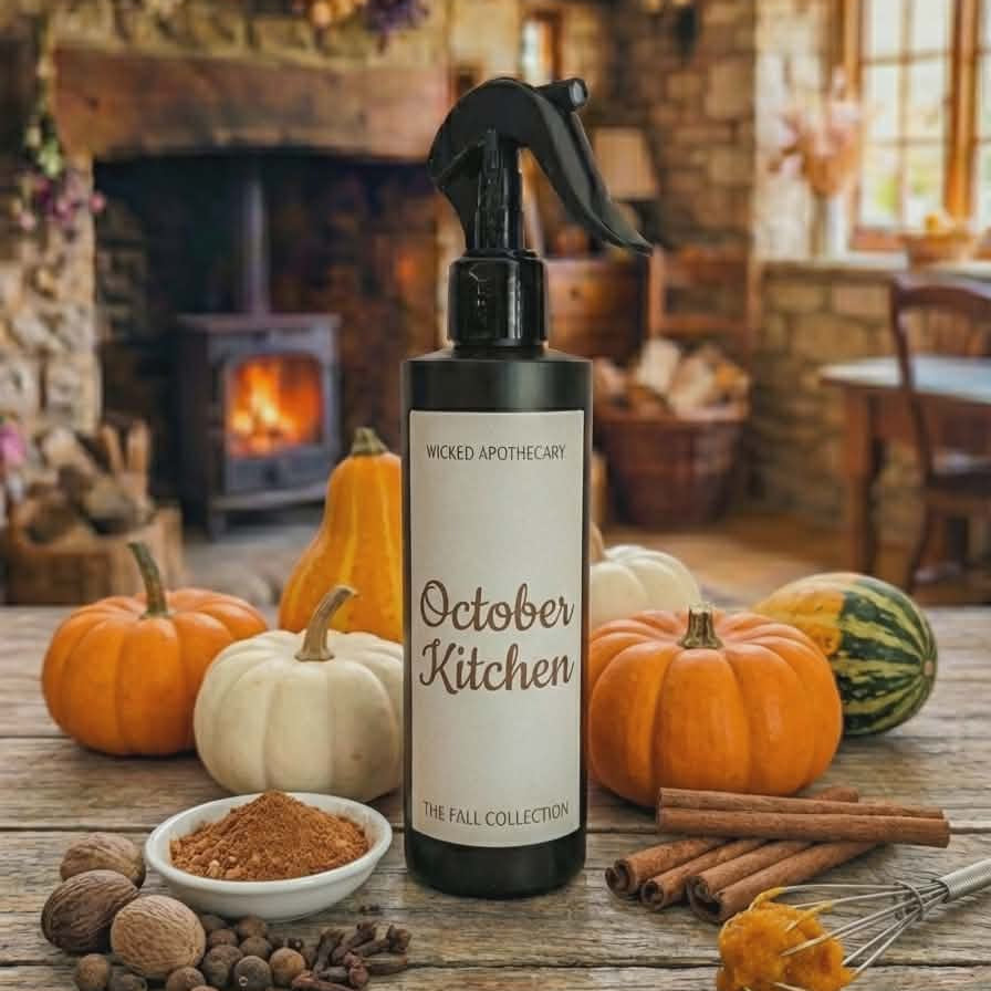 Bottle of 'October Kitchen' spray on a wooden table with pumpkins and spices in a cozy room.