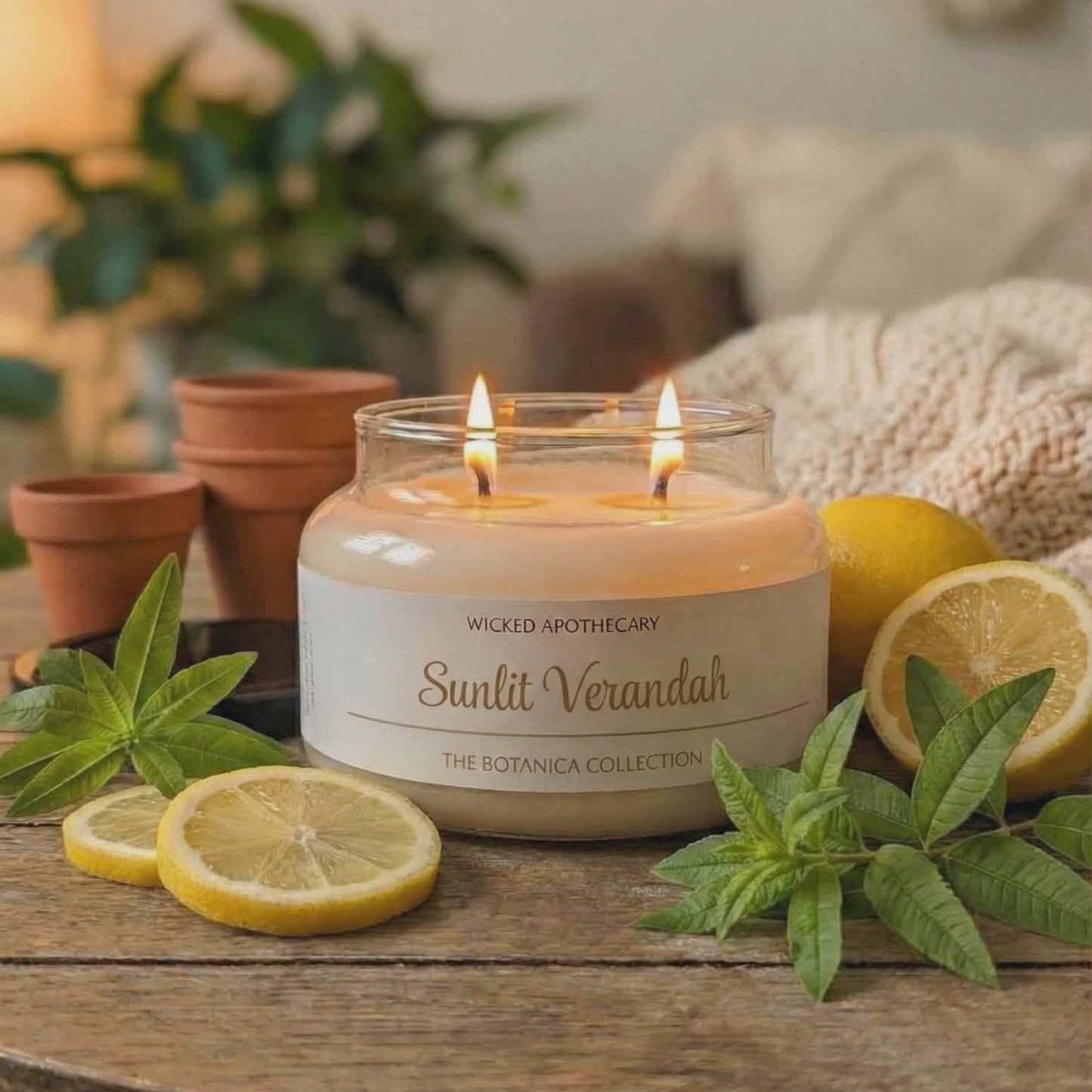 Candle labeled 'Suntit Verandah' on a wooden table with lemons and plants.