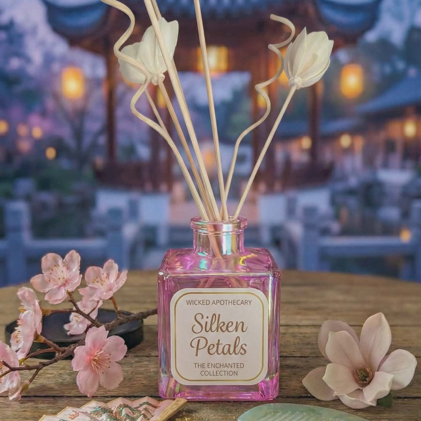 Decorative diffuser with 'Silken Petals' on a wooden table with flowers and a blurred background