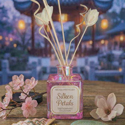 Decorative diffuser with 'Silken Petals' on a wooden table with flowers and a blurred background
