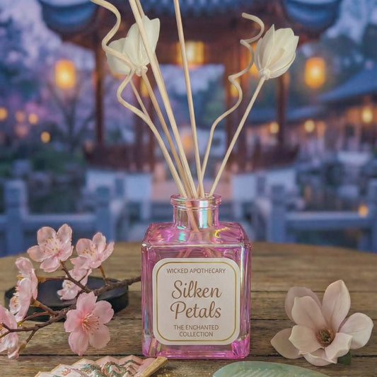 Decorative diffuser with 'Silken Petals' on a wooden table with flowers and a blurred background