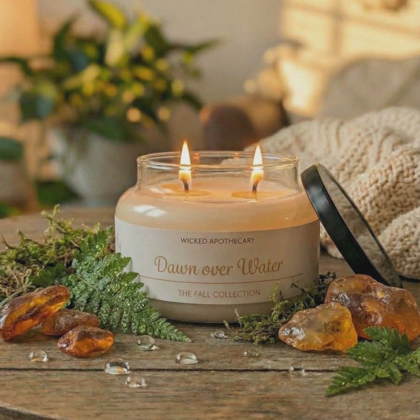 Candle in a glass jar labeled 'Wicked Apothecary' on a wooden surface with decorative elements.