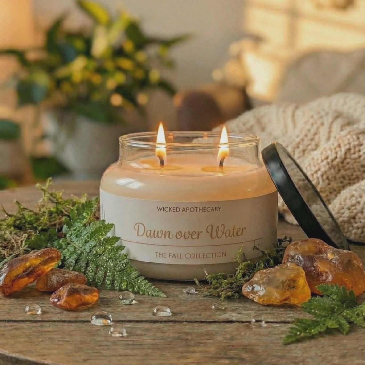 Candle in a glass jar labeled 'Wicked Apothecary' on a wooden surface with decorative elements.