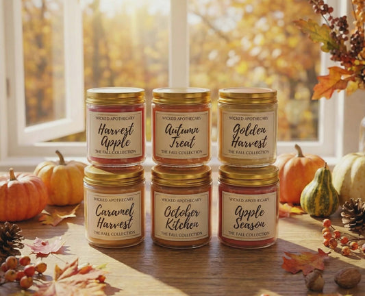 Collection of candles with autumn-themed labels on a wooden surface with pumpkins and leaves.