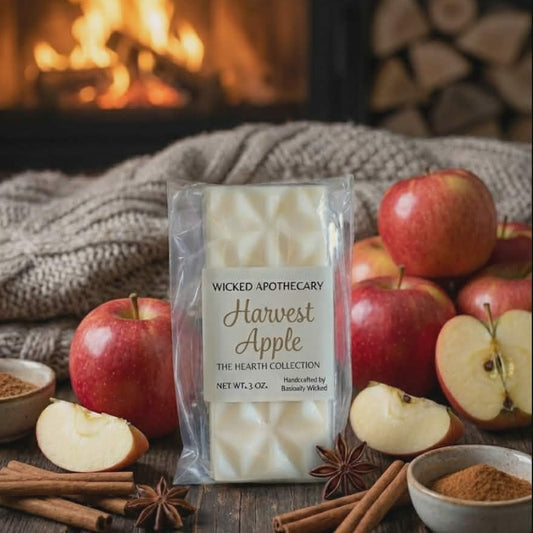 Wicked Apothecary Harvest Apple candle packaging with apples, cinnamon, and a fireplace in the background