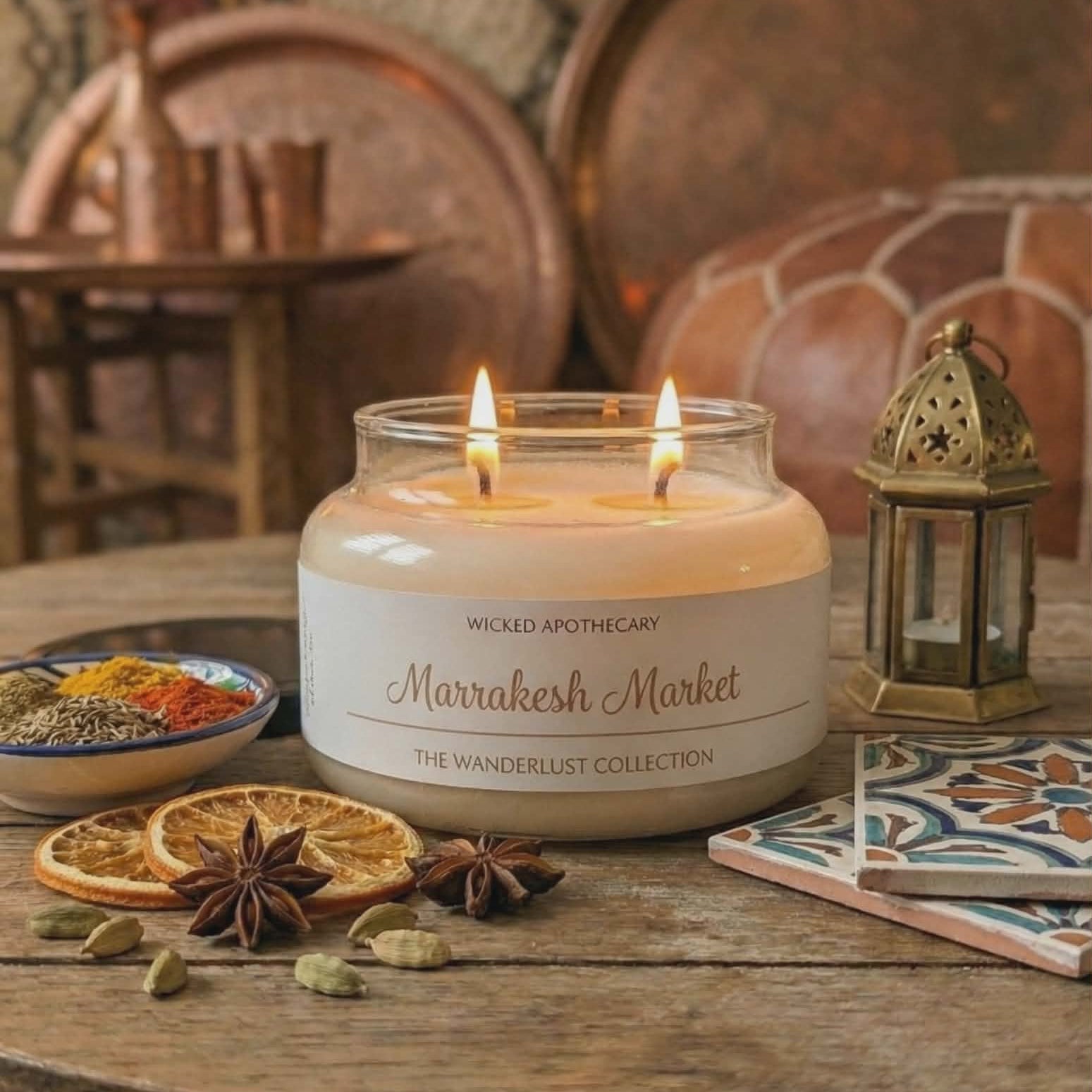 Candle labeled 'Marrakesh Market' on a wooden table with decorative elements.