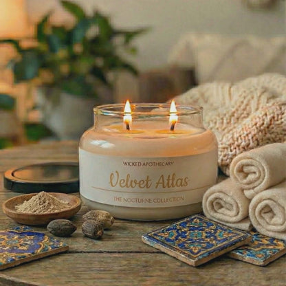 Candle labeled 'Velvet Atlas' on a wooden table with decorative items and plants in the background