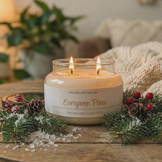 Candle labeled 'Evergreen Pines' from Wicked Apothecary on a wooden table with decorative elements.