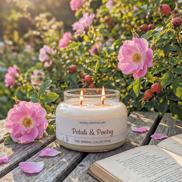 Candle labeled 'Petals & Poetry' on a wooden surface with flowers and an open book in the background.