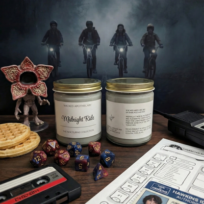 Two candles labeled 'Midnight Rite' on a table with gaming supplies and a dark background.